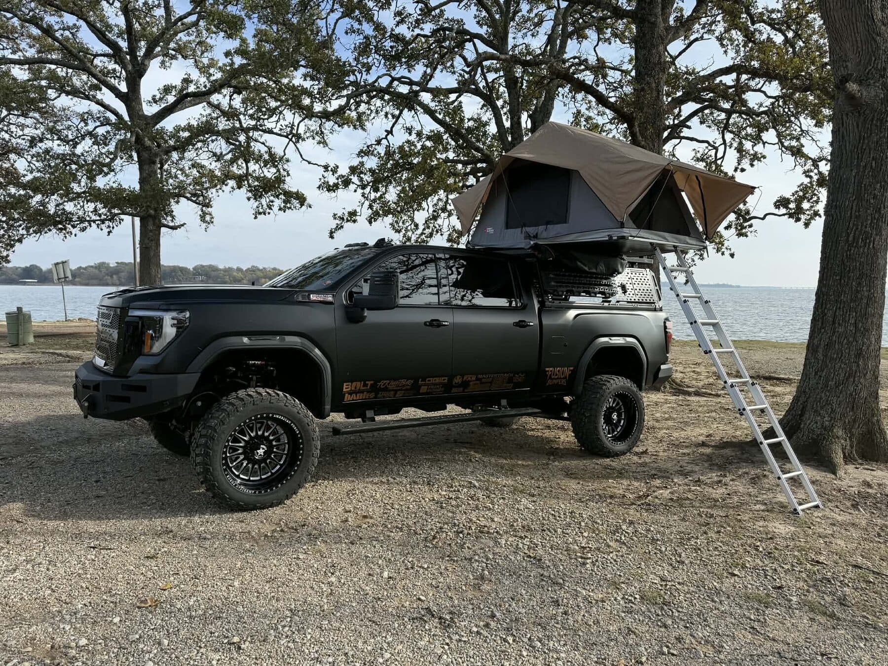 Lifted GMC 2500HD with rooftop tent lakeside